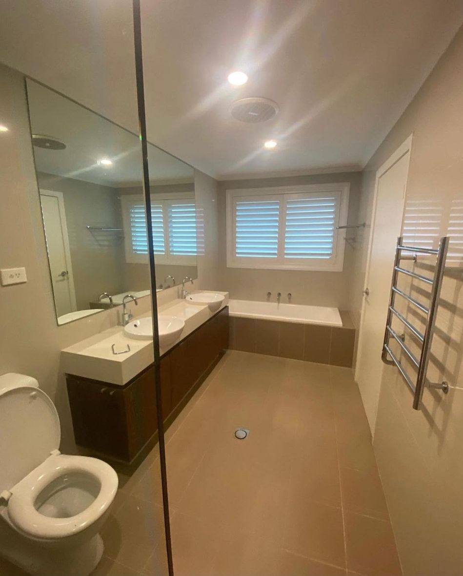 Completed bathroom renovation by INNA GROUP — frameless shower and stone tiling.
