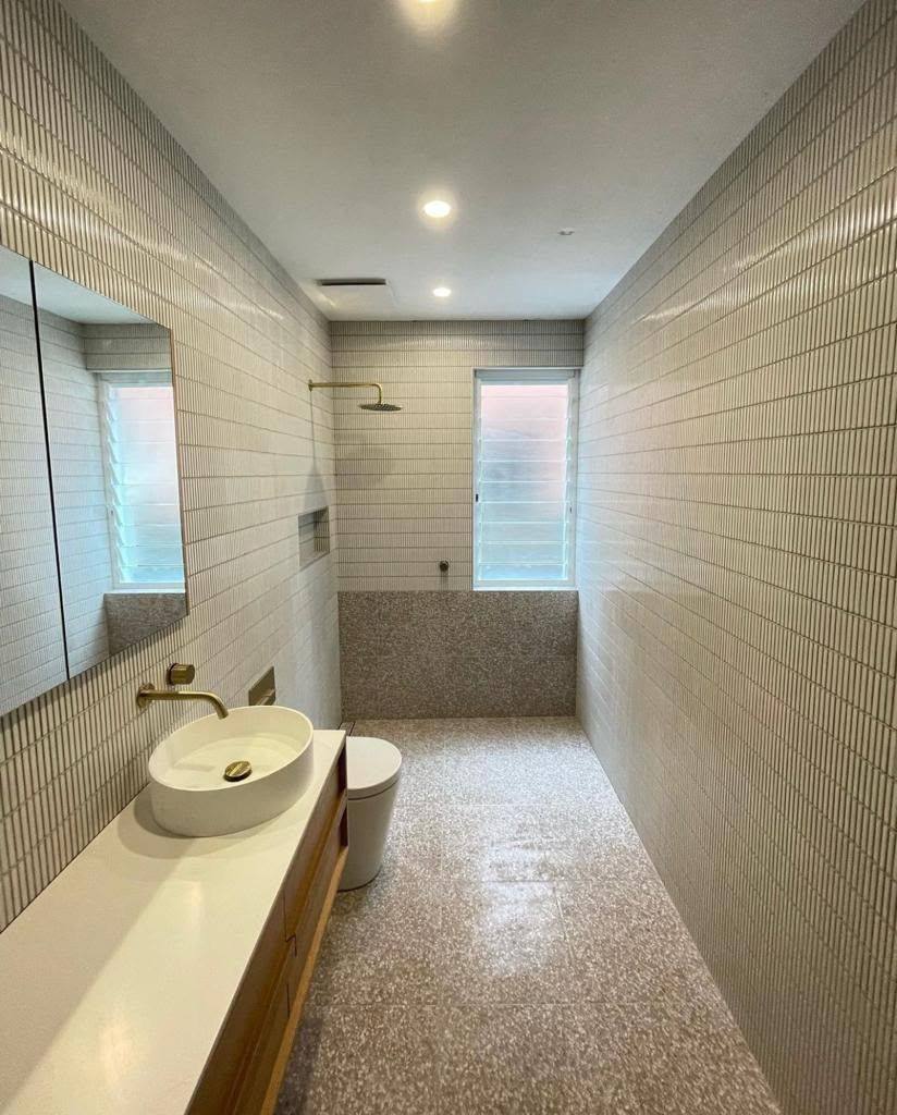 Completed bathroom renovation by INNA GROUP — frameless shower and stone tiling.