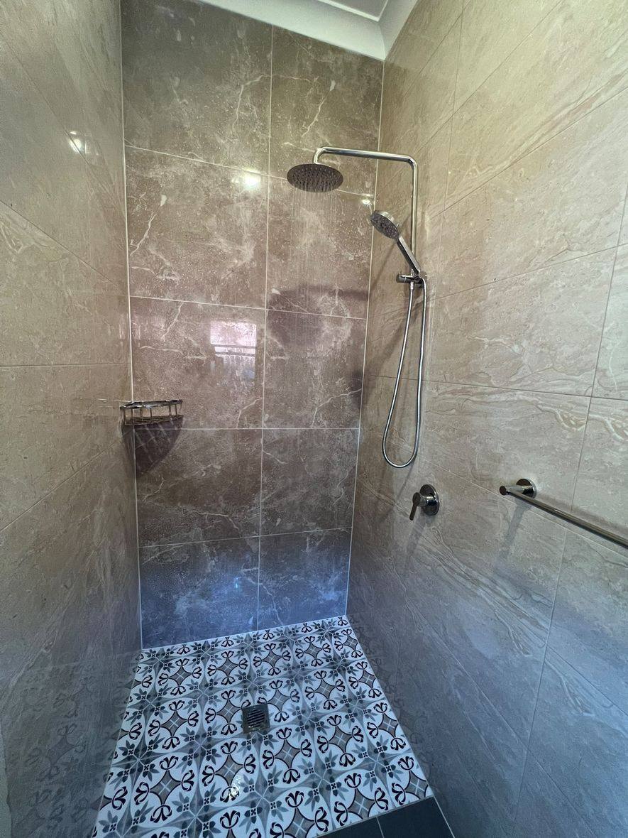 Completed bathroom renovation by INNA GROUP — frameless shower and stone tiling.